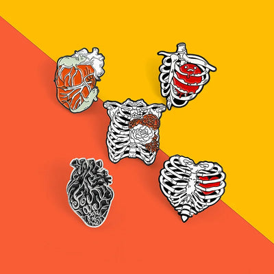 Five anatomical heart and ribcage pins on a two-tone orange and yellow background
