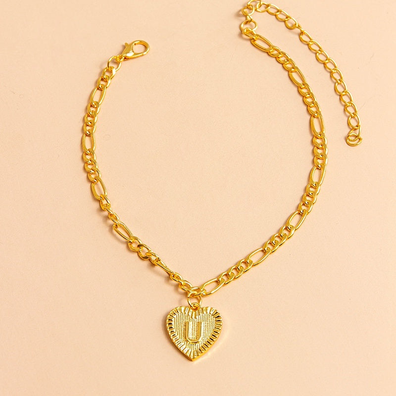 Gold chain necklace with a heart-shaped pendant letter U on a beige background