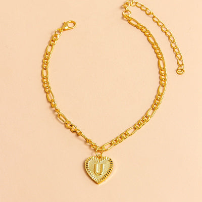 Gold chain necklace with a heart-shaped pendant letter U on a beige background