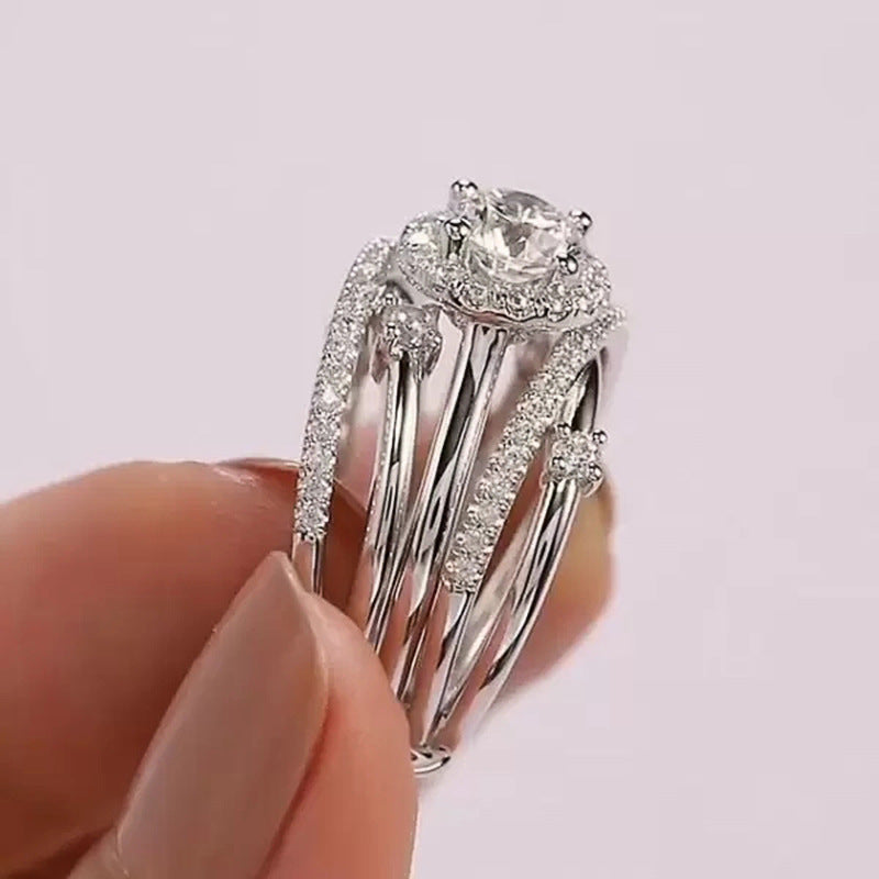 Silver ring with a large zircon held between fingers against a light background