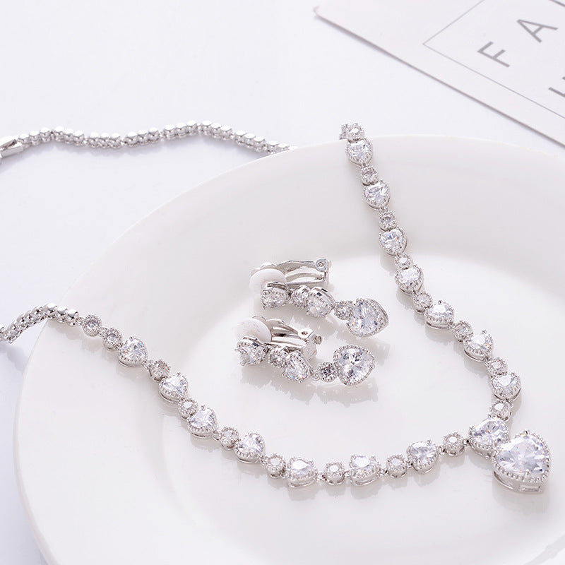 Silver jewelry set with necklace, bracelet, and earrings on a white surface.
