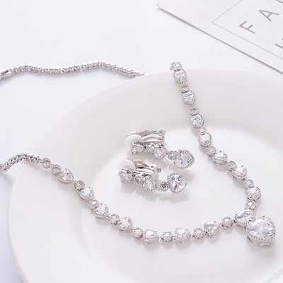 Silver jewelry set with necklace, bracelet, and earrings on a white surface.
