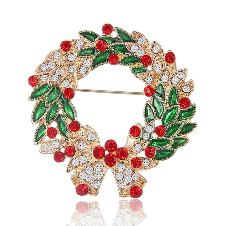Decorative brooch with green leaves, red berries, and gold accents on a white background