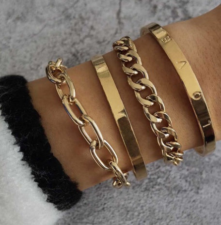 Gold bracelets on a wrist with a neutral background