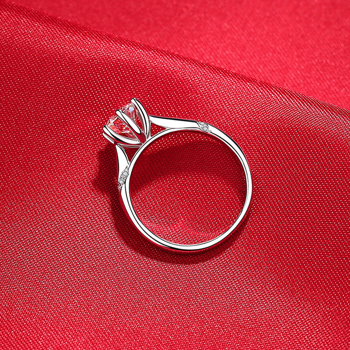 Silver ring with a pink gemstone on a red fabric background