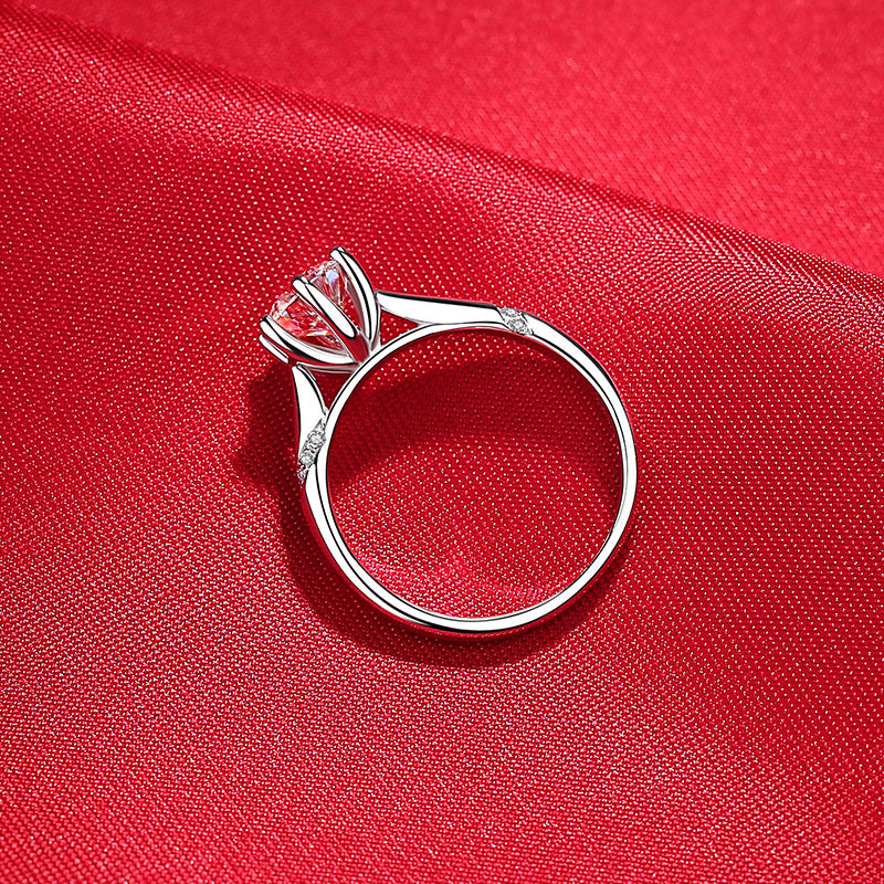 Silver ring with a pink gemstone on a red fabric background