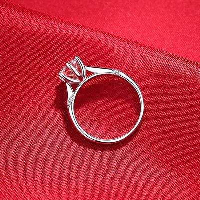 Silver ring with a pink gemstone on a red fabric background