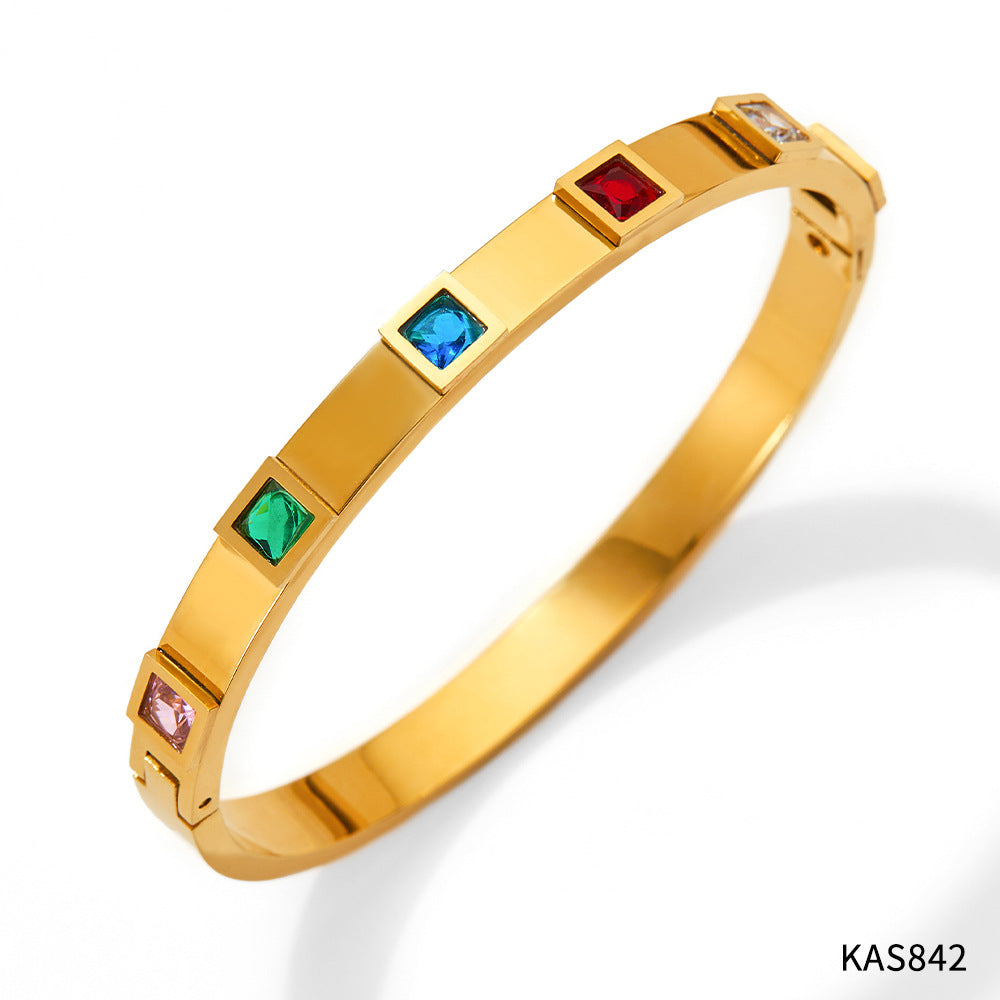 Gold bracelet with colorful gemstones on a white background