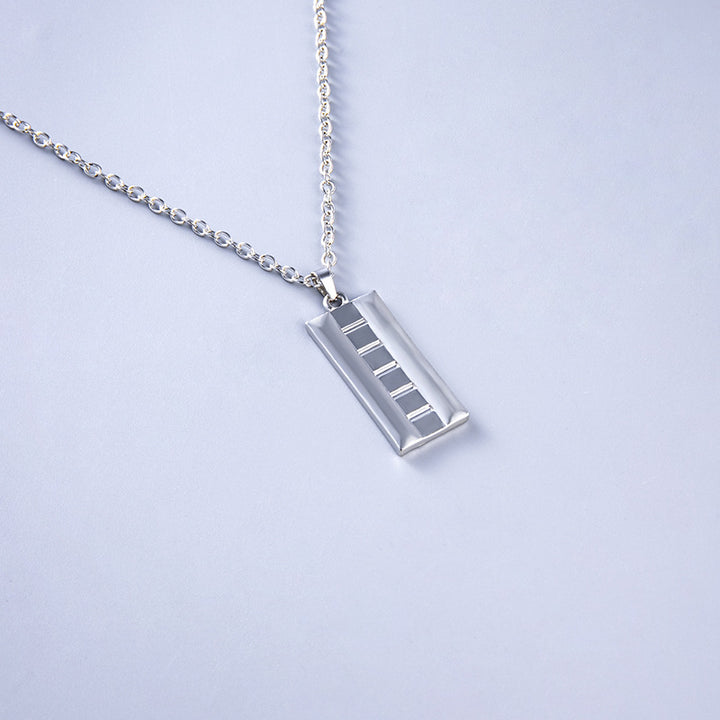 Silver necklace with a rectangular pendant on a light gray background
