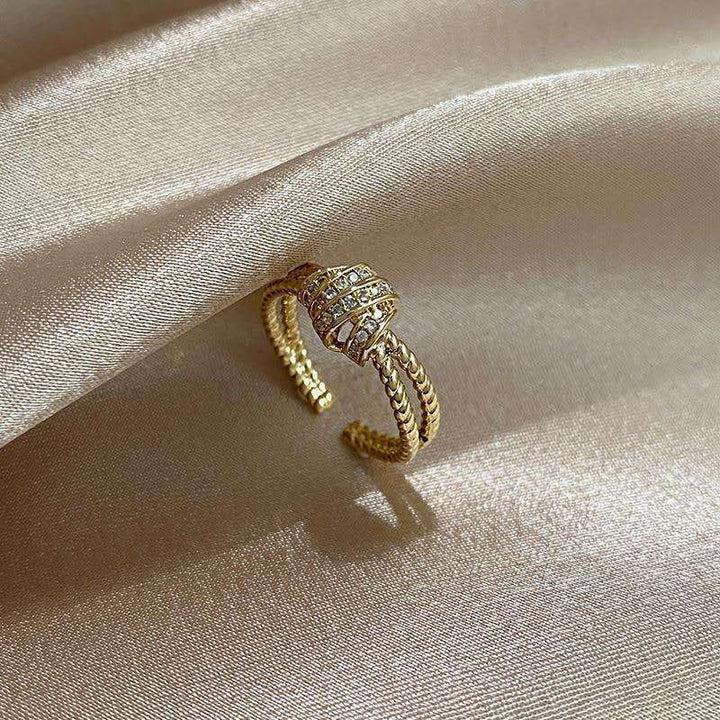 Gold ring with gemstones on a beige satin background