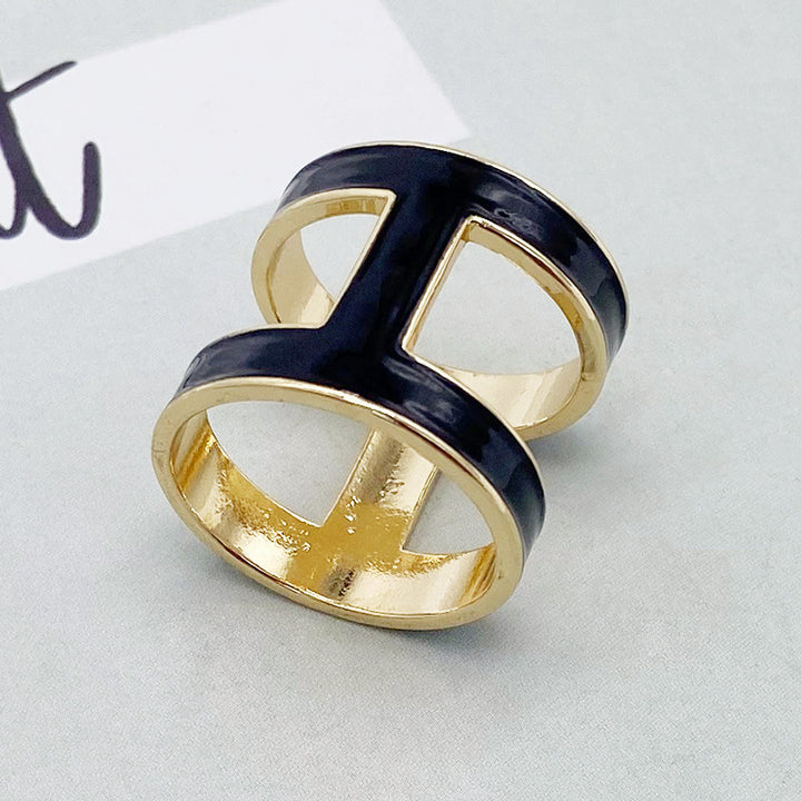 Two gold and black rings stacked on a light gray surface.