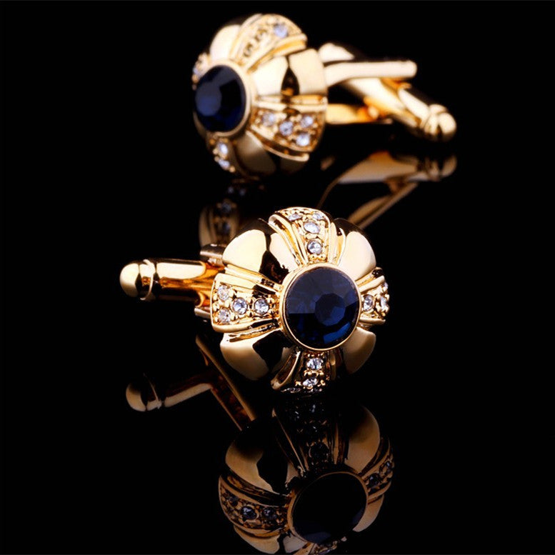 Gold cufflinks with blue gemstones on a black background