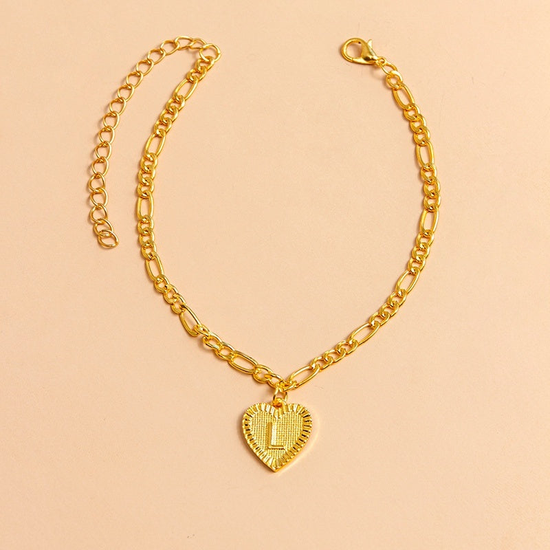 Gold chain necklace with a heart-shaped pendant letter L on a beige background