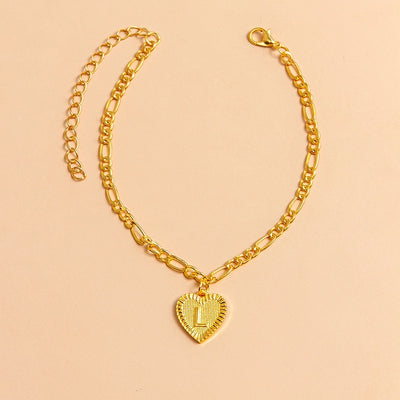 Gold chain necklace with a heart-shaped pendant letter L on a beige background