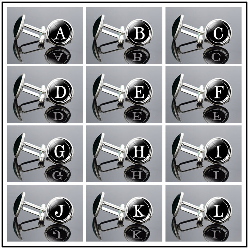 Cufflinks with letter labels arranged in a grid on a reflective surface.
