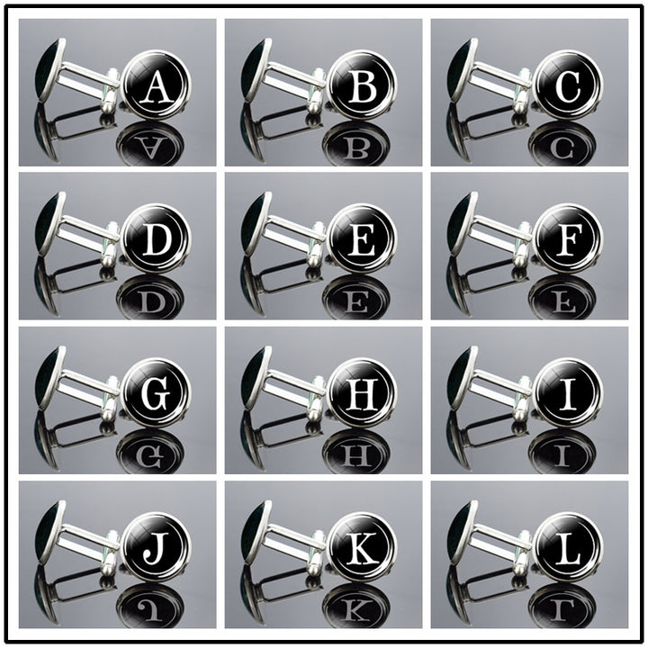 Cufflinks with letter labels arranged in a grid on a reflective surface.