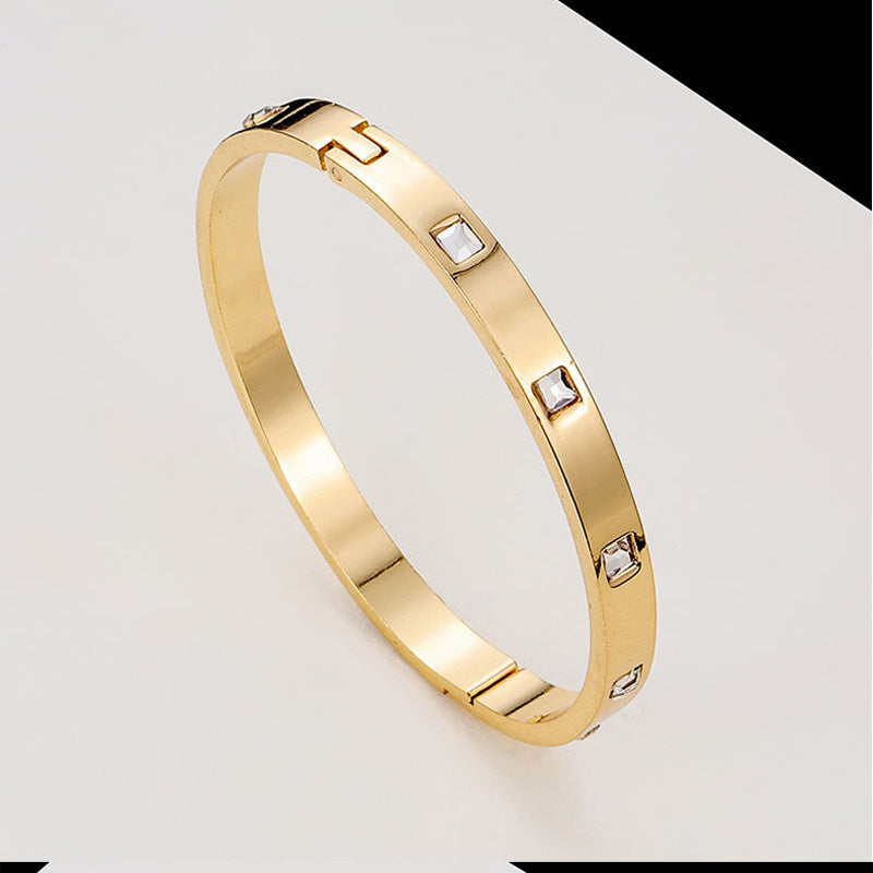 Gold bracelet with embedded diamonds on a light gray background