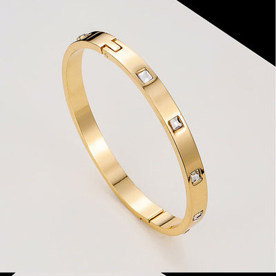 Gold bracelet with embedded diamonds on a light gray background