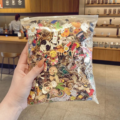 Hand holding a clear bag filled with various colorful pins in a casual setting.