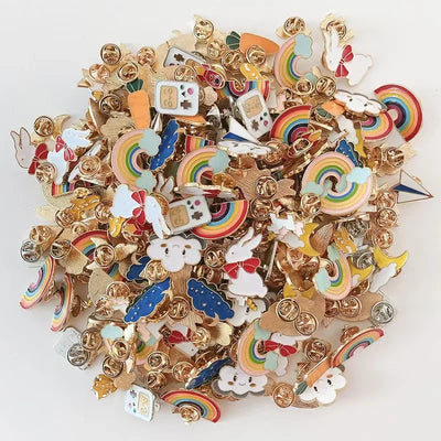 Collection of colorful enamel pins with rainbow, cloud, and animal designs on a white background