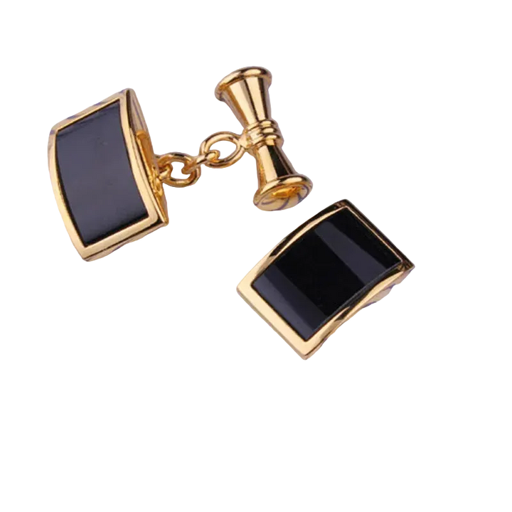 Gold cufflinks with black stones on a striped fabric background