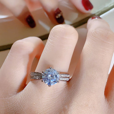 Close-up of a hand wearing a diamond ring with a blurred background