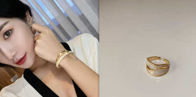 Woman wearing a gold bracelet with a close-up of a gold ring on a white background.