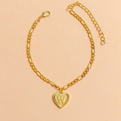 Gold chain bracelet with a heart-shaped charm letter W on a beige background