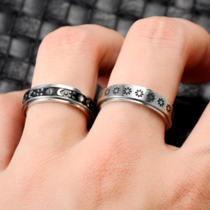 Two silver rings with intricate designs on a person's fingers against a blurred background.
