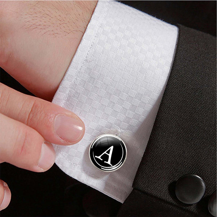 Cufflink with a logo on a white cuff against a black suit background