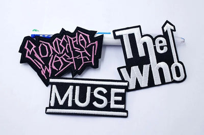 Three patches with 'Muse', 'The Who', and stylized text on a white background