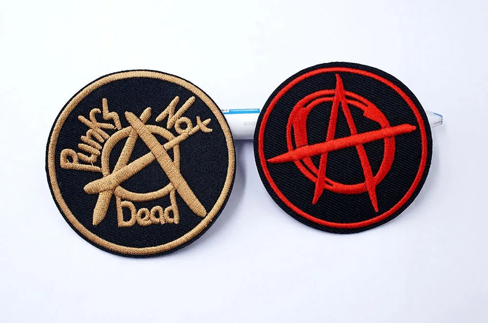 Two circular patches with 'Punks Not Dead' and an anarchy symbol on a white background.
