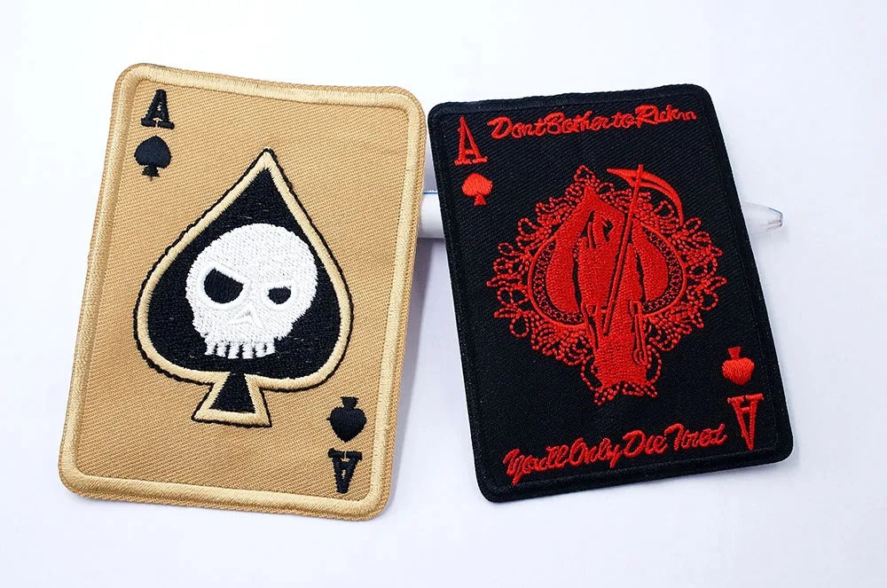 Two card-themed patches with skull and red design on a white background