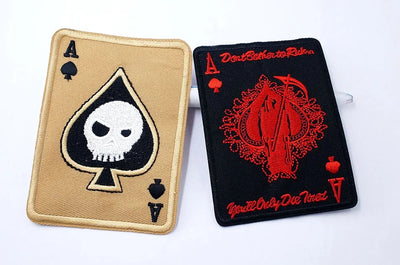Two card-themed patches with skull and red design on a white background