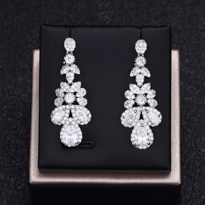Pair of white zircon earrings on a black box with a dark textured background