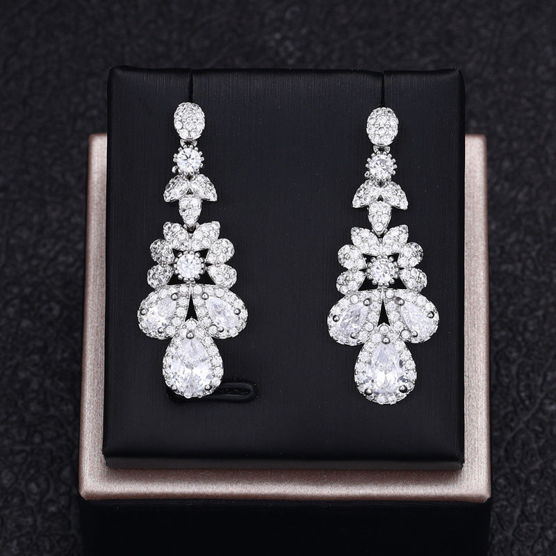 Pair of white zircon earrings on a black box with a dark textured background