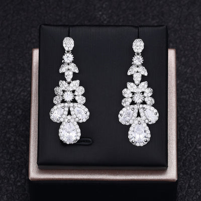 Pair of white zircon earrings on a black box with a dark textured background