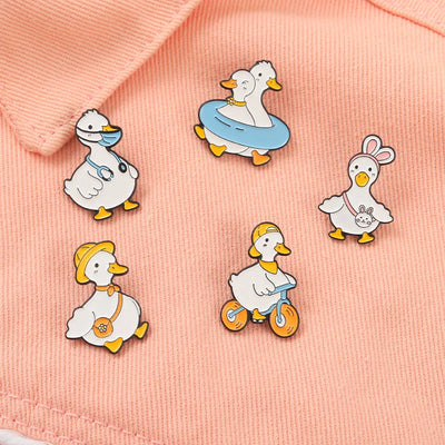 Set of cartoon duck pins on a pink fabric background