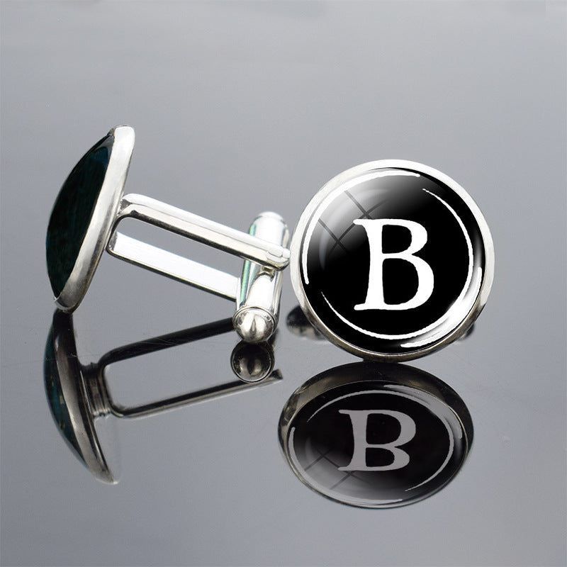 Cufflinks with a black round emblem featuring the letter &