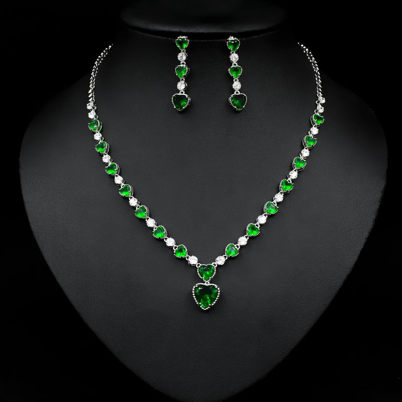 Jewelry set with necklace and earrings featuring green and clear stones on a black background