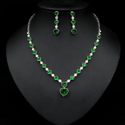 Jewelry set with necklace and earrings featuring green and clear stones on a black background