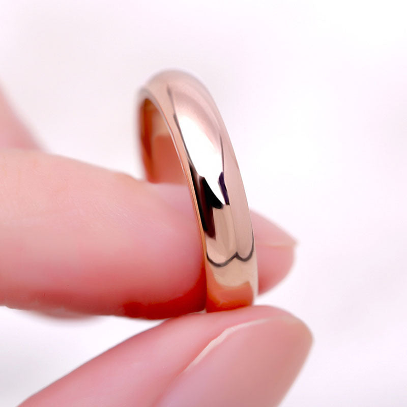 Rose gold ring being worn on a finger against a white background