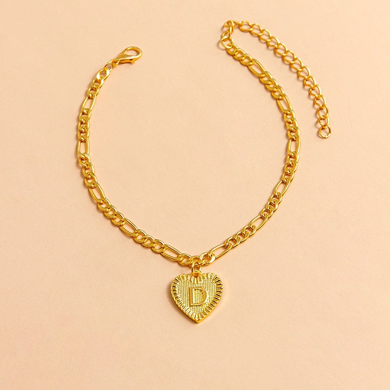 Gold chain necklace with a heart-shaped pendant letter D on a beige background