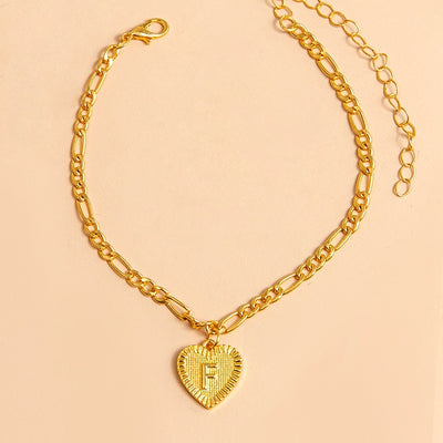 Gold chain necklace with a heart-shaped pendant letter F on a beige background