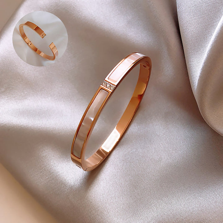 Rose gold bracelet on a soft beige fabric background