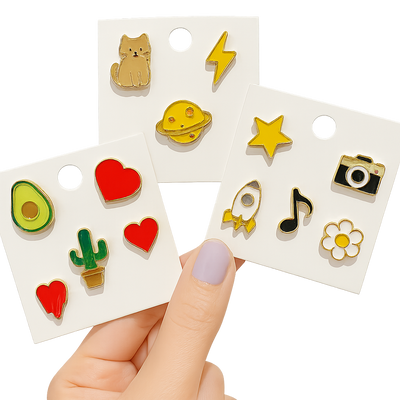 Set of colorful enamel pins on display cards held by a hand.