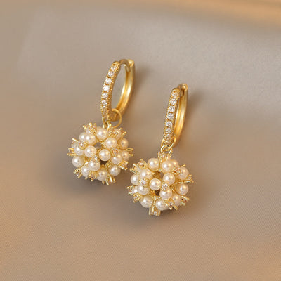 Gold earrings with pearl-like beads on a beige background