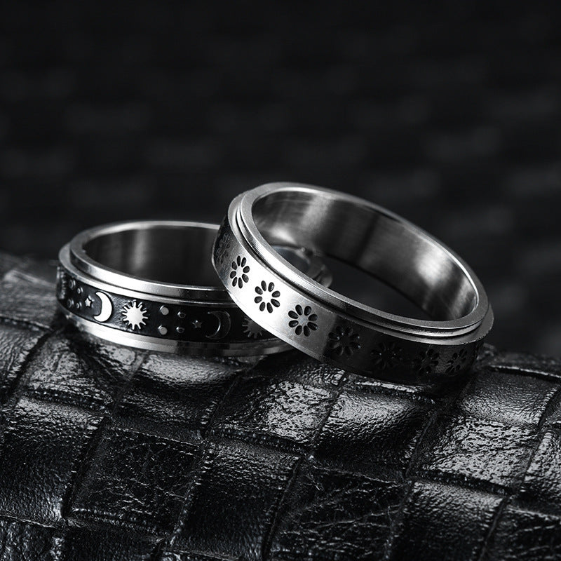 Two silver rings with intricate designs on a textured black surface