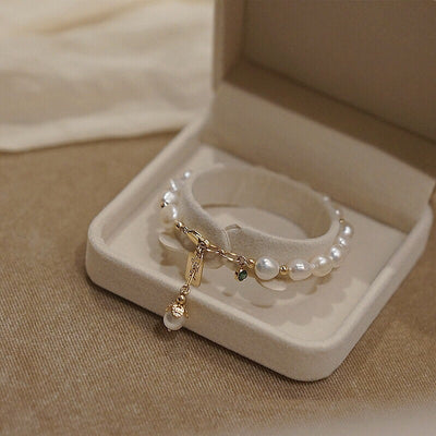 Pearl bracelet with gold charm in a jewelry box on a beige fabric background