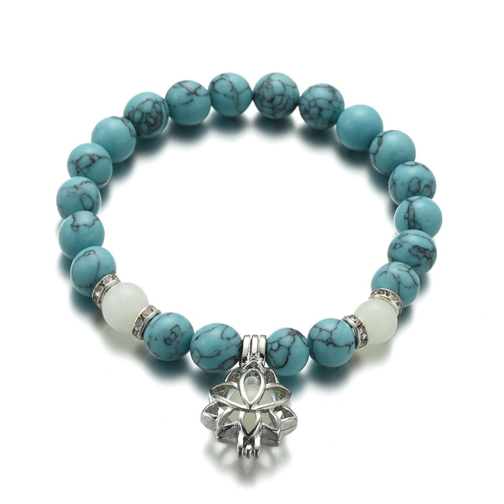 Turquoise beaded bracelet with a silver lotus charm on a white background